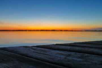 Sunset over the ocean, across a boardwalk.