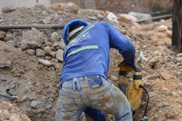 Construction worker amidst dirt and rocks.