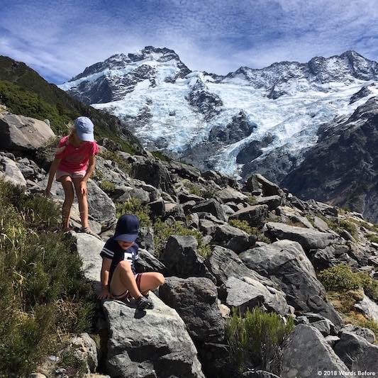 Kids scrambling over rocks in front of Mount Sefton